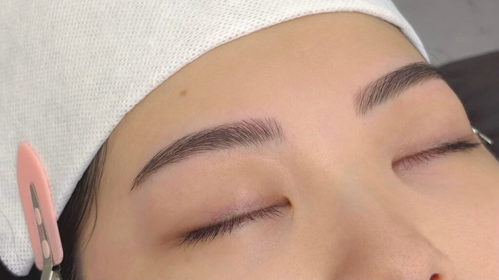 目を閉じた女性の、眉尻にかけてすっきり整えた平行アーチ眉のアップ