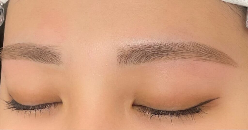 目を閉じた目元のアップ。左右の眉を自然な平行アーチに整えた眉