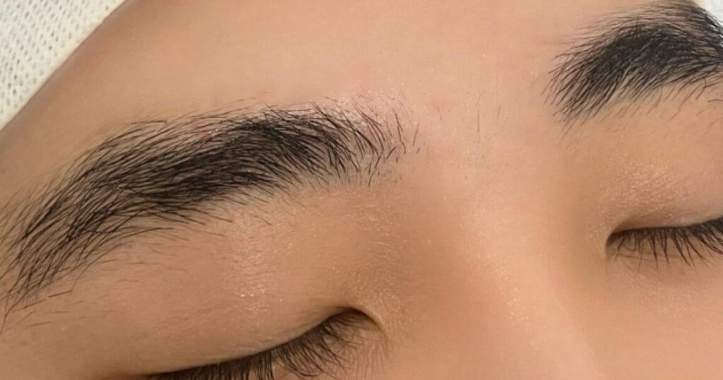 目を閉じた目元と、整える前の伸びた眉のアップ